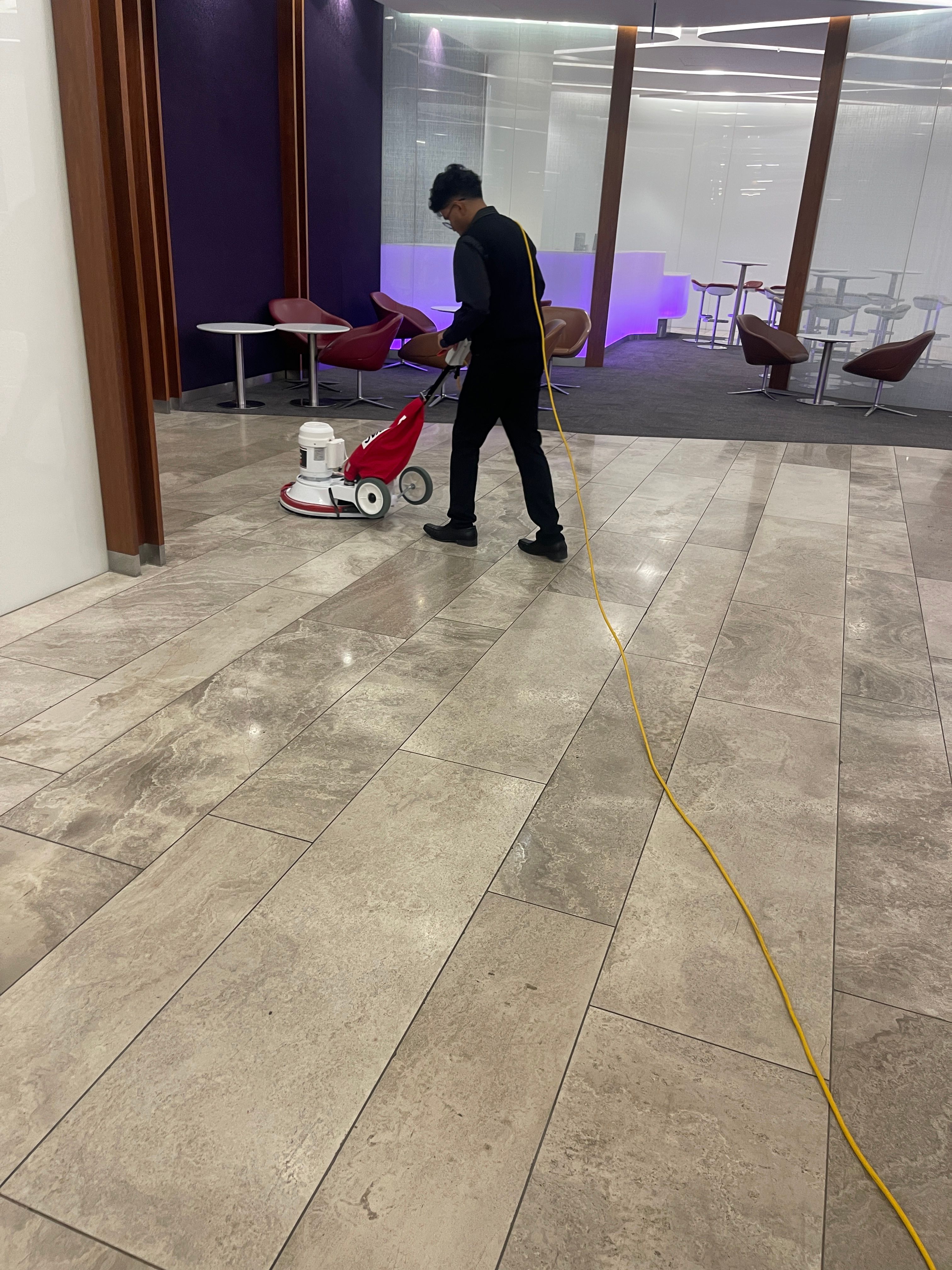 A cleaner carrying out hard-floor maintenance in a workplace lobby