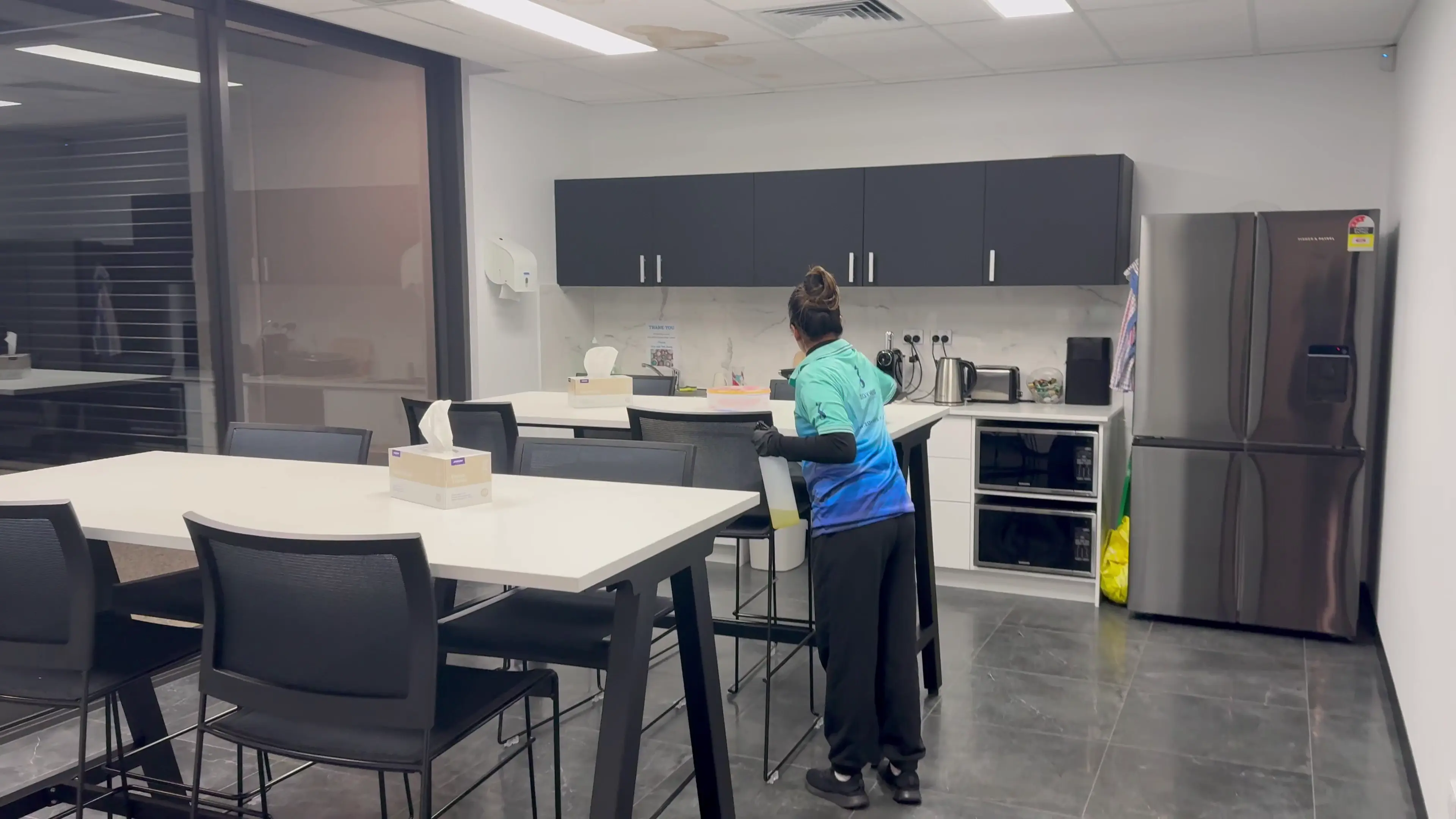 A Zavvers cleaner cleaning tables and chairs in a staff breakroom