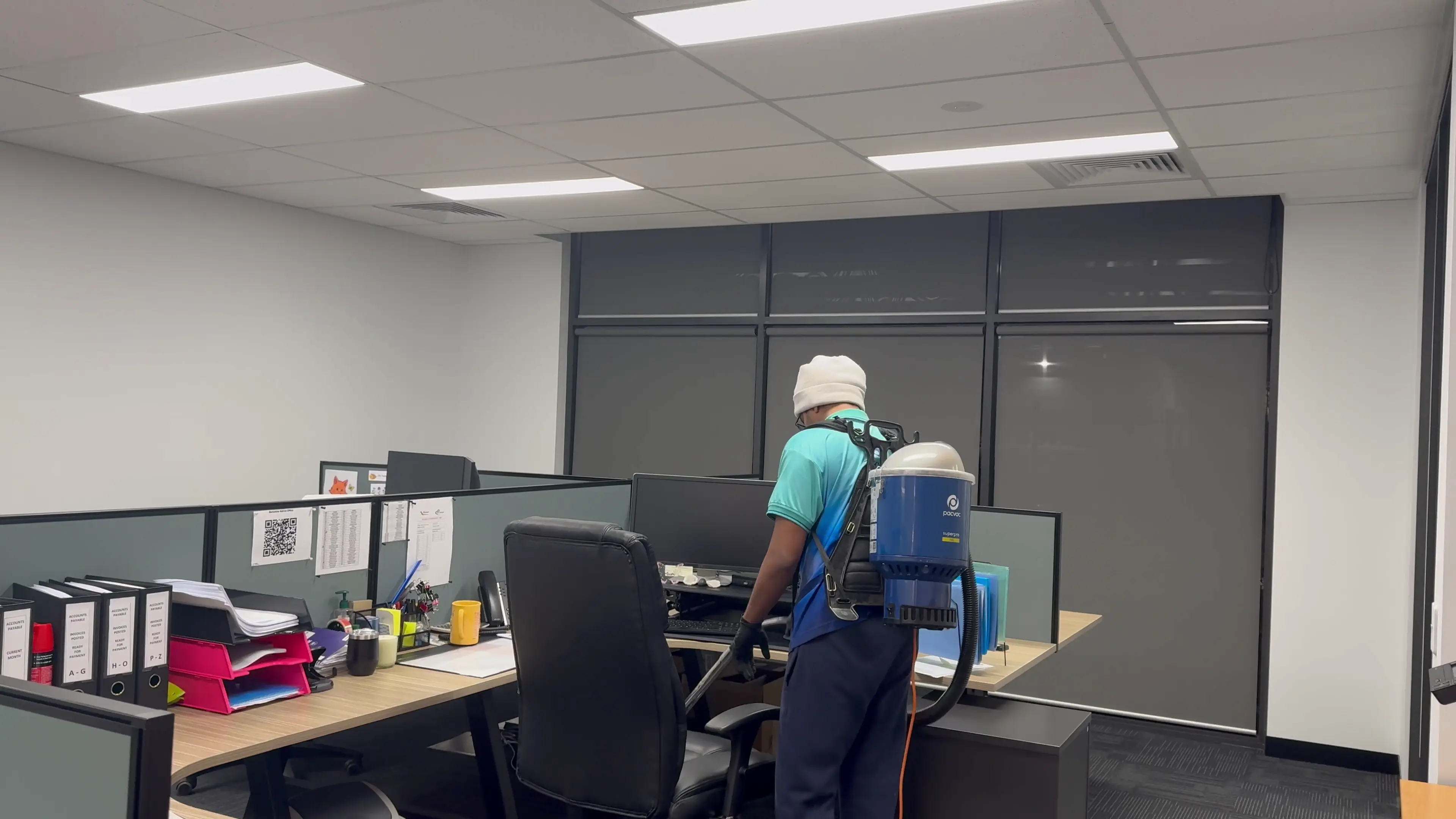 A Zavvers cleaner vacuuming around office desks and chairs