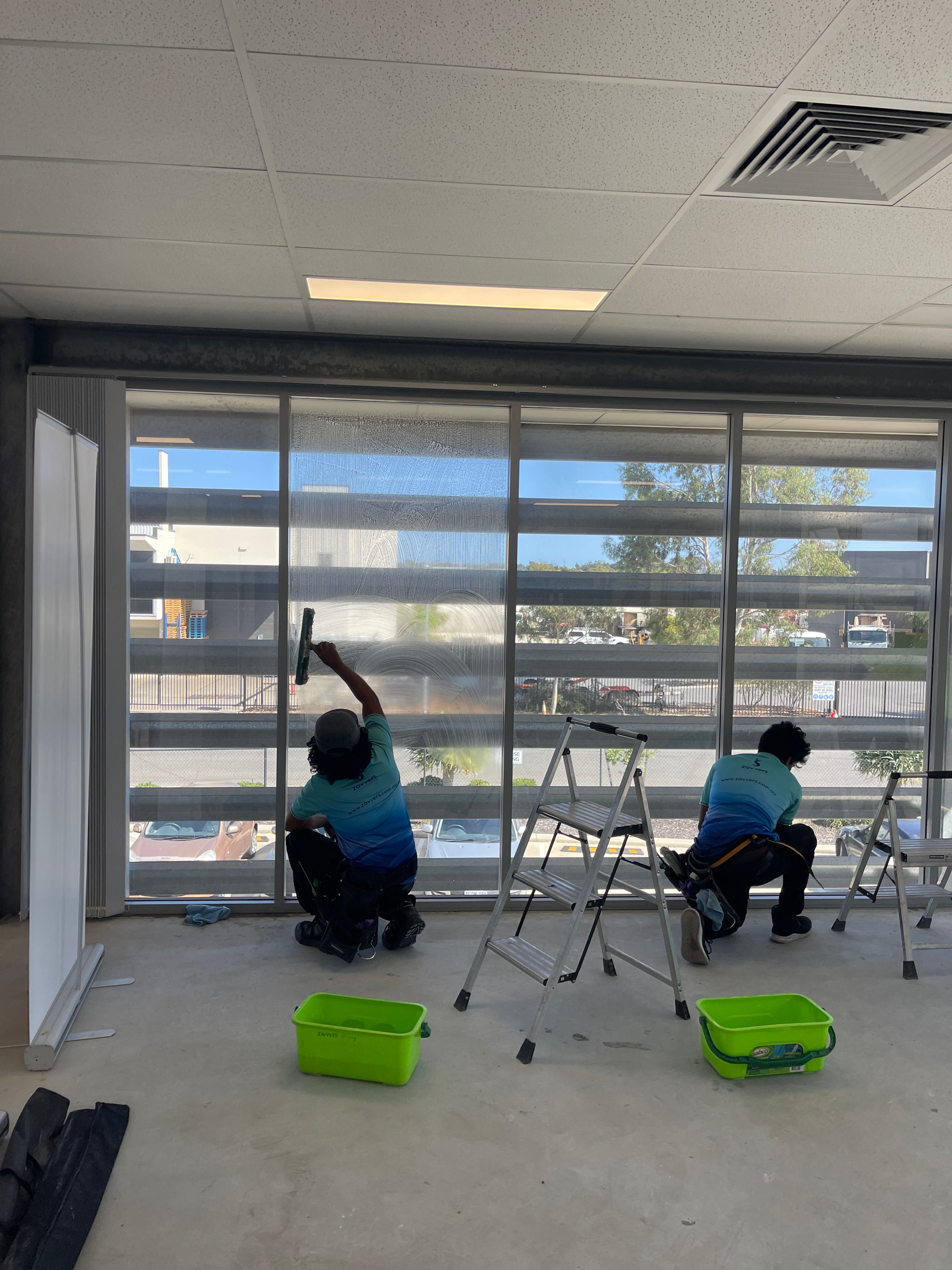 Two Zavvers team members cleaning workplace glass